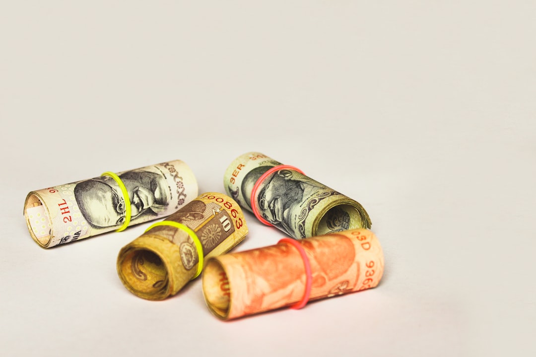 간디 초상이 그려진 인도 루피 지폐 다발이 어지럽게 놓여 있고, 고환율 속 청년의 대출·저축·투자 전략을 상징함